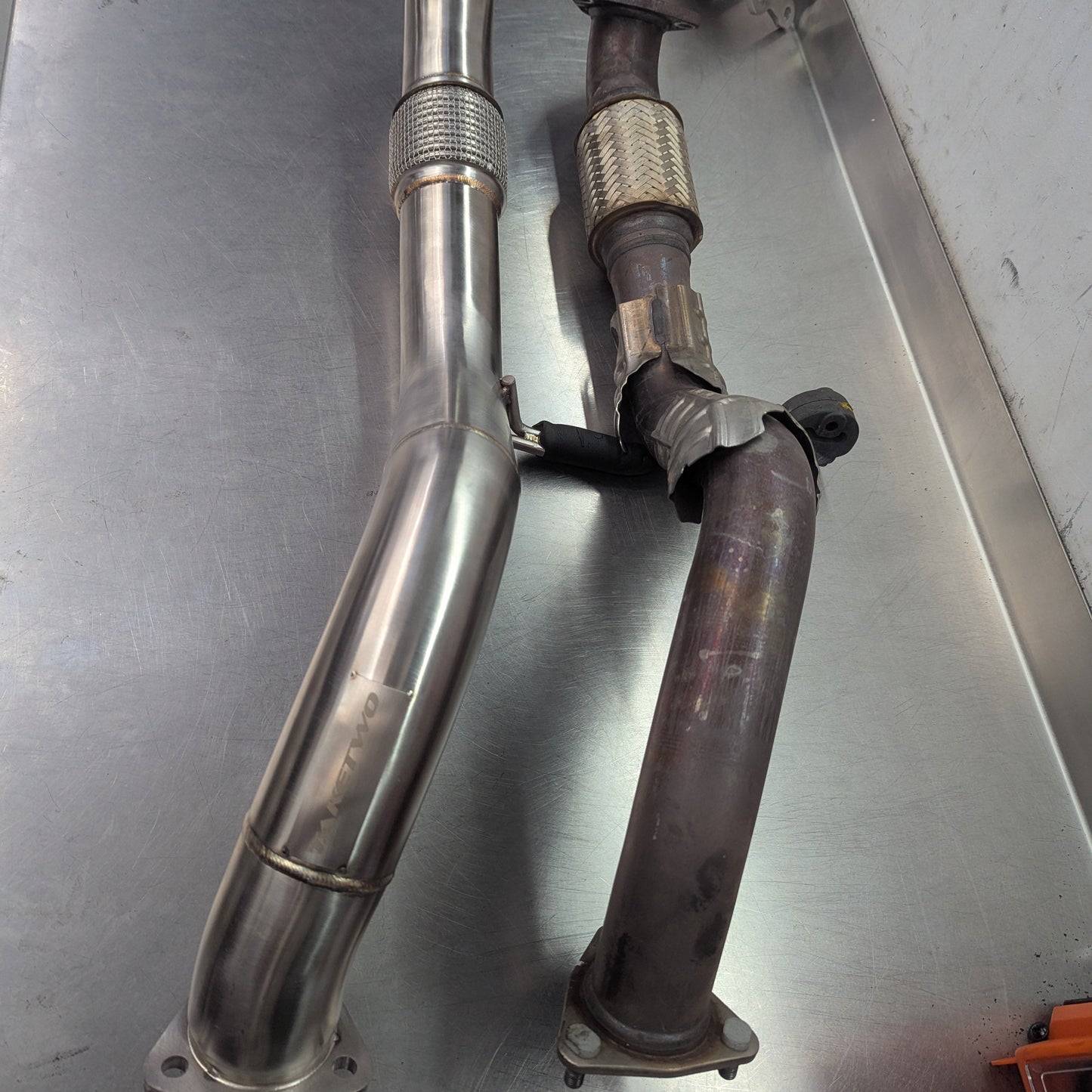 Two metal exhaust pipes on a metallic surface