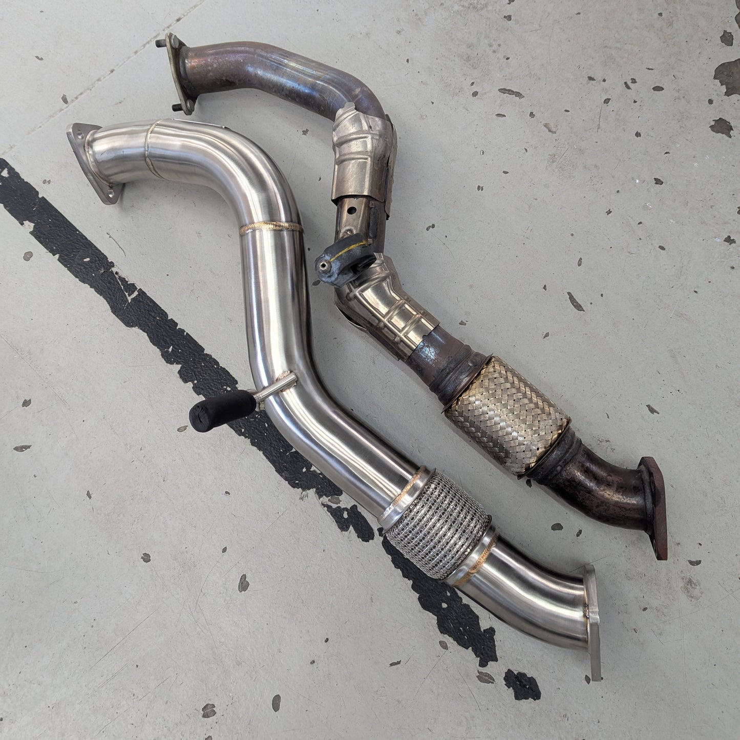 Two metal exhaust pipes on a concrete floor